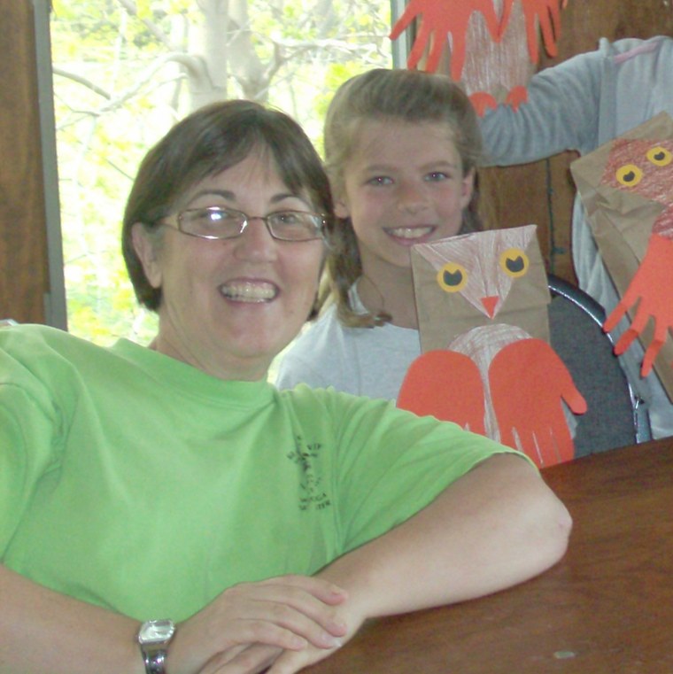 A woman and a young volunteer smiling with handmade paper-bag crafts